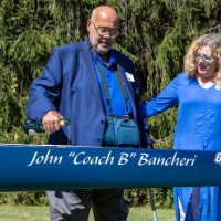 Former head coach John Bancheri and his wife Christine stand near boat that says John "Coach B" Bancheri